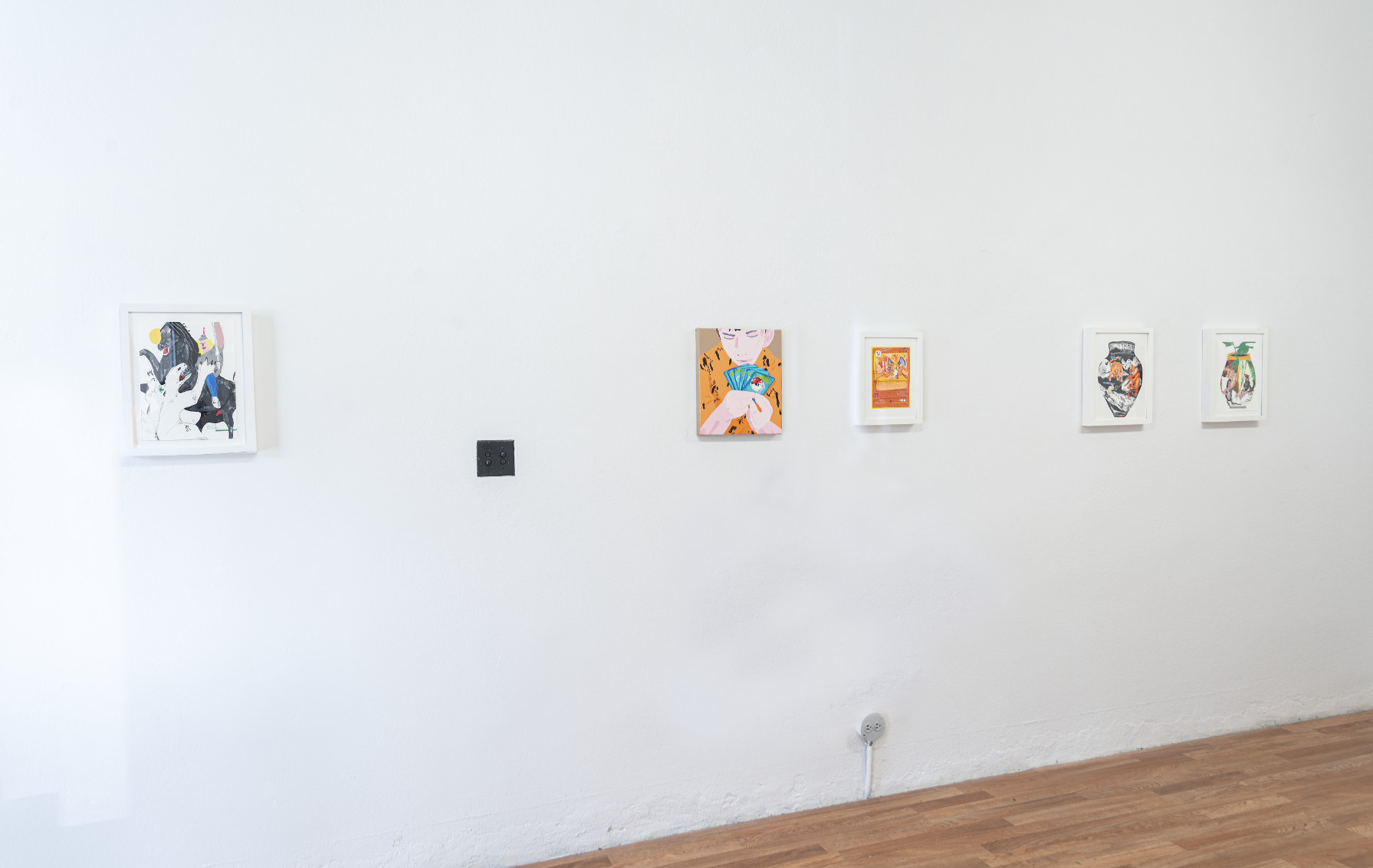 Indoor installation with white walls and wooden floor, small framed collages on the wall