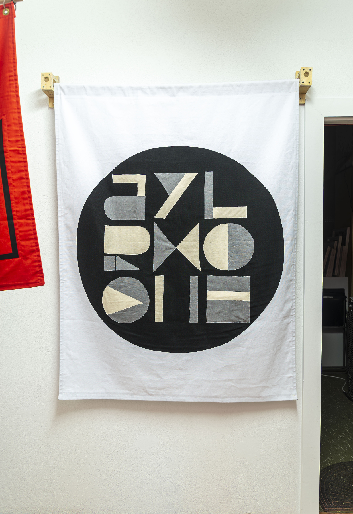 installation view: colorful flags hang in a clean well lit space with wooden floors and white walls